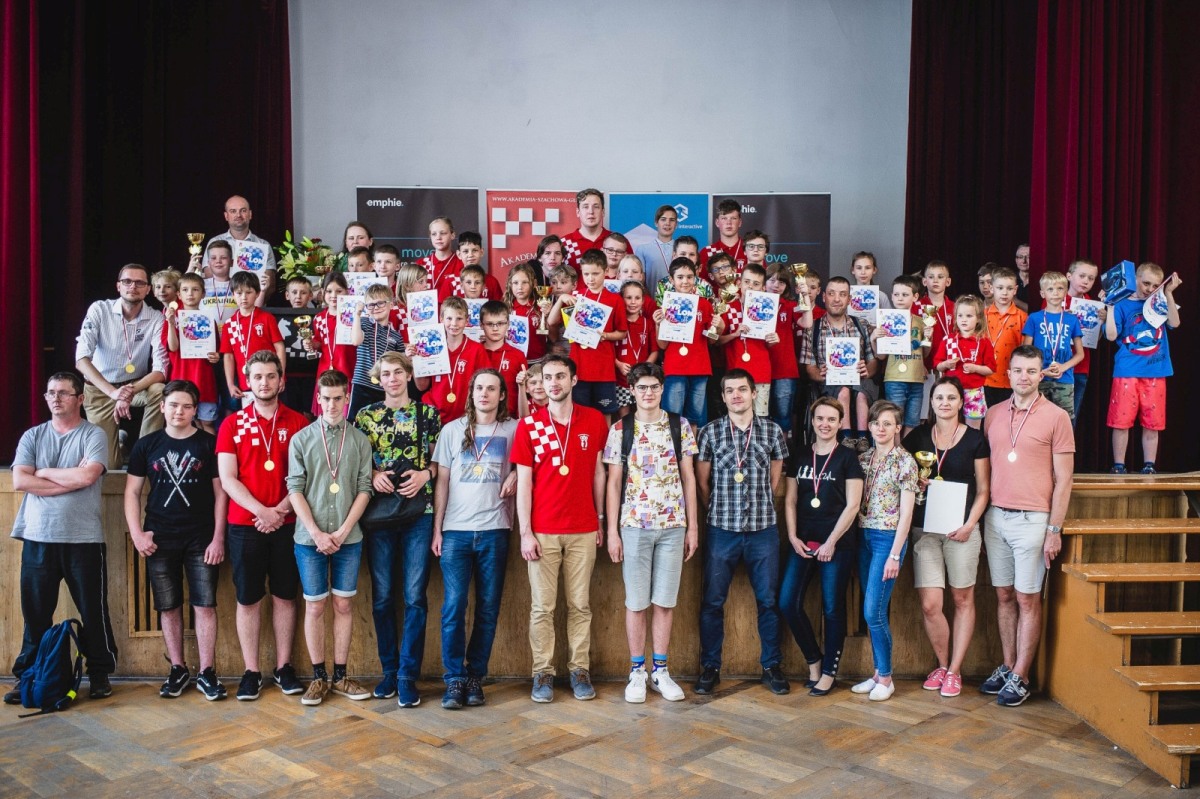 Grupowe zdjęcie dzieci i trenerów na sali z medalami i dyplomami, Akademia Szachowa Gliwice