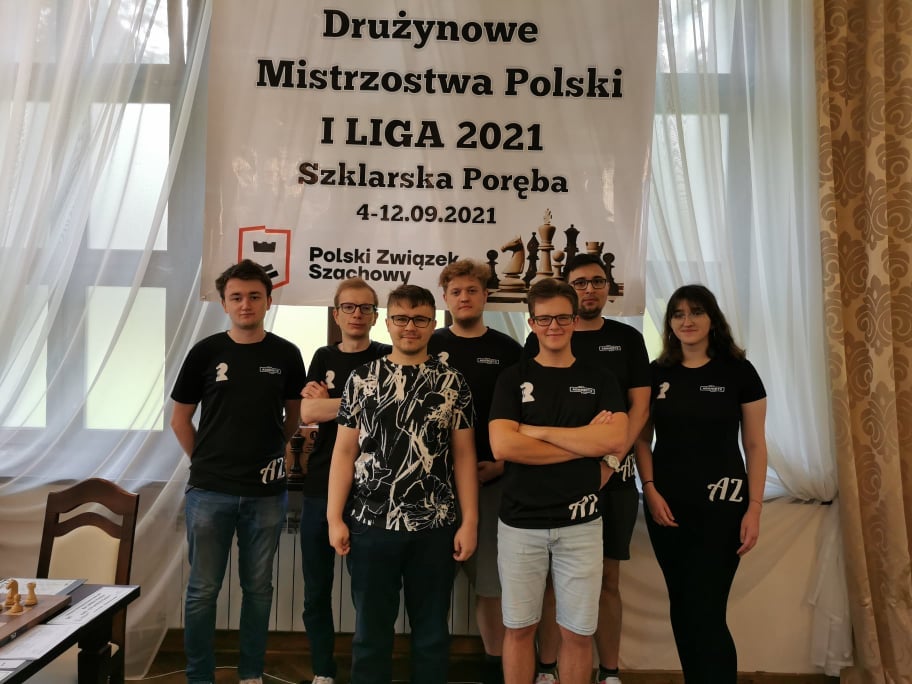 Grupa w koszulkach klubowych pozuje przed banerem mistrzostw polski, klub szachowy Strzelec Strzelce Opolskie