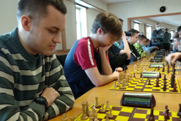 Zawodnicy grający w szachy przy rzędzie stolików z zegarami, UKS Gekon Nysa