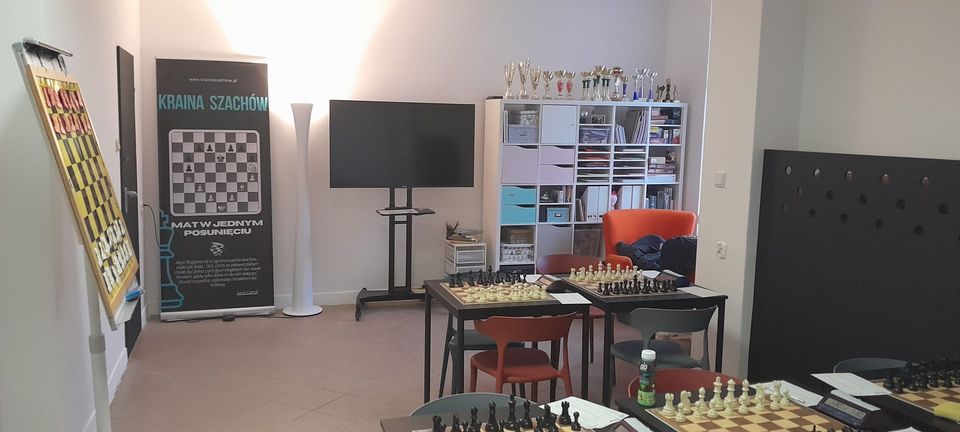 Sala klubowa z szachownicami na stolikach i regałami w tle, klub szachowy Kraina Szachów z Wrocławia