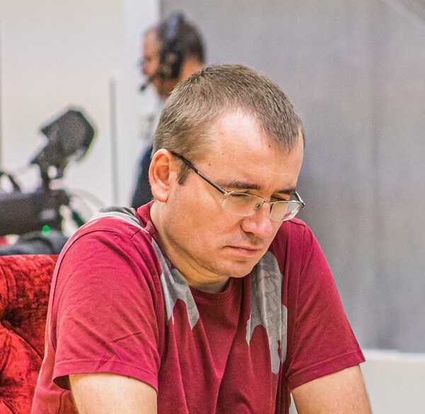 Mężczyzna w czerwonej koszulce skupiony podczas partii szachów, trener szachów Maciej Świcarz z Wrocławia