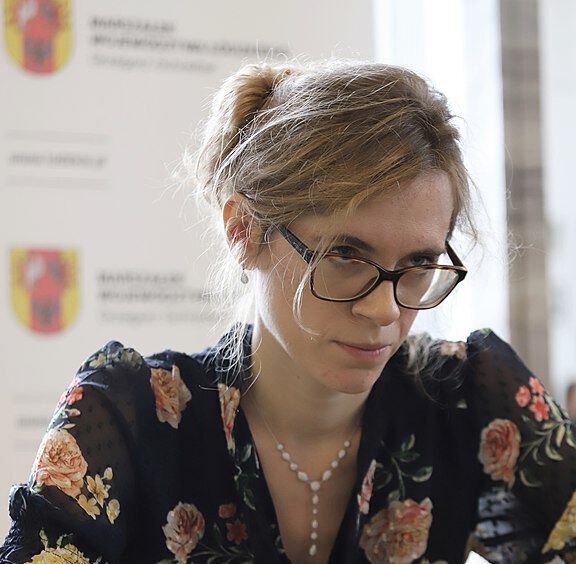 Kobieta w okularach siedzi przy stole podczas spotkania, trener szachów Marta Bartel z Warszawy