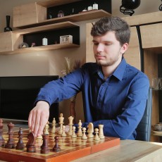 Mężczyzna w niebieskiej koszuli wykonuje ruch na szachownicy, trener szachów Marcin Pasieka z Krakowa